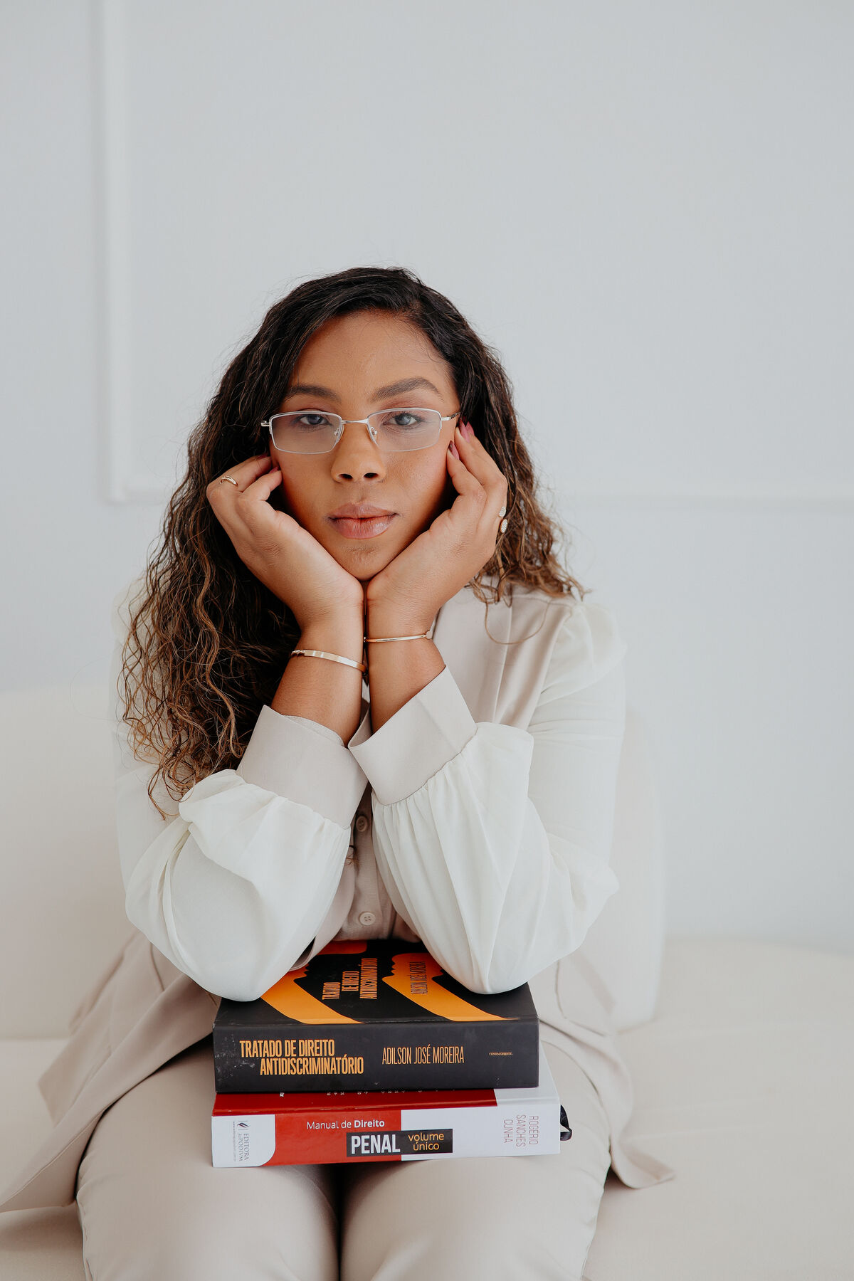 Beatriz Vieira apoiada sobre livros de Direito Penal e Direito Antidiscriminatório